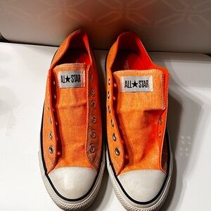 A pair of turquoise and a pair of orange All Star Converse shoes.